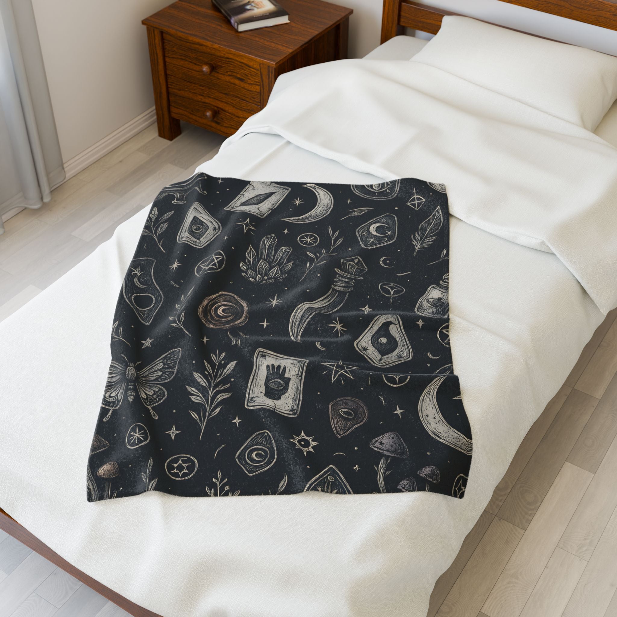 Black patterned blanket draped over a bed with white bedding.