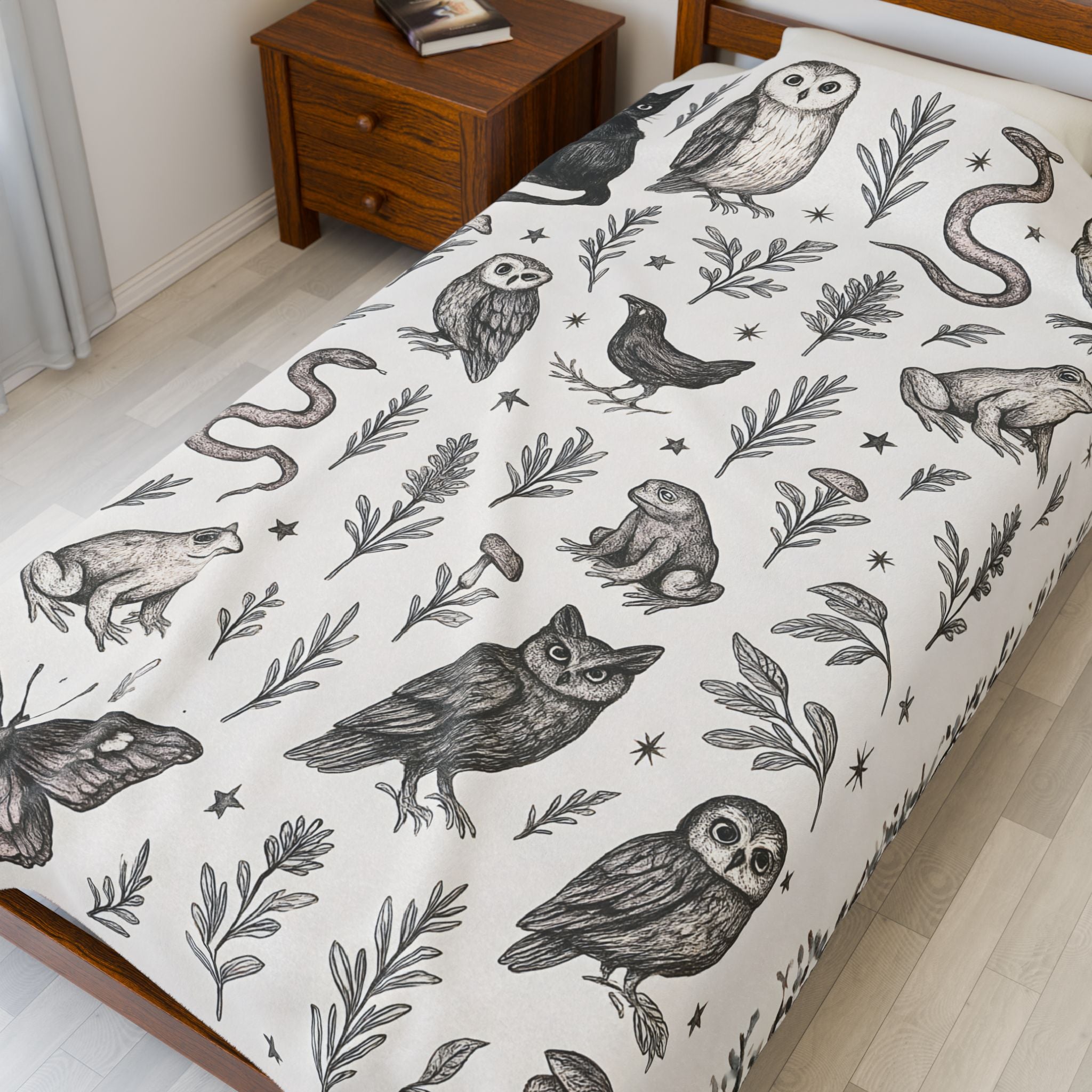 Bedspread with black and white nature-themed design featuring birds and plants on a bed in a room.